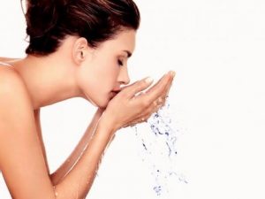 γυναίκα που πλένει το πρόσωπό της με καθαρό νερό