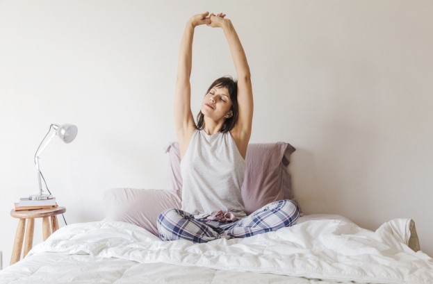 κοπέλα κάνει stretching κρεβάτι πρωινές συνήθειες