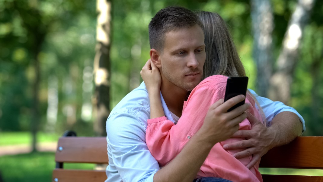 άντρας είναι στο κινητό ενώ αγκαλιάζει μια γυναίκα