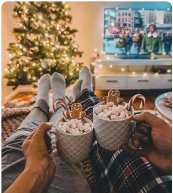 ζευγάρι βλέπει χριστουγεννιάτικη ταινία με ζεστές σοκολάτες