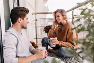 ζευγάρι κάθεται στο μπαλκόνι και συζητάει πίνοντας καφέ